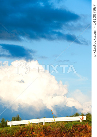 A summer scene of guardrails and cumulonimbus clouds on a hill in Biei, Hokkaido. A summer scene of guardrails and cumulonimbus clouds on a hill in Biei, Hokkaido. 141097967