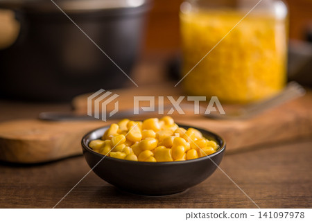Bowl of Sweet Corn Kernels on Wooden Table with Jar of Canned Corn in Background Bowl of Sweet Corn Kernels on Wooden Table with Jar of Canned Corn in Background 141097978