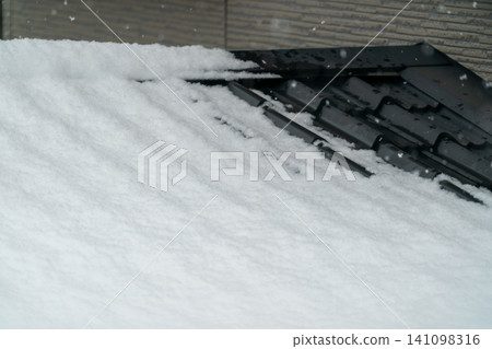 黑色瓦片屋頂被厚厚的積雪覆蓋 141098316