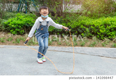 Happy Asian girl skipping rope outdoors in park, active child exercising and healthy lifestyle concept Happy Asian girl skipping rope outdoors in park, active child exercising and healthy lifestyle concept 141098447