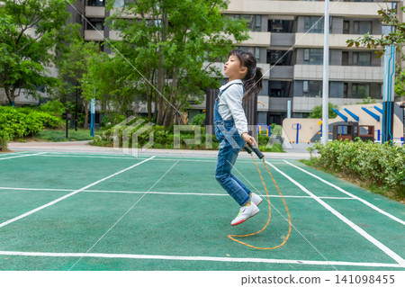 Happy Asian girl skipping rope outdoors in park, active child exercising and healthy lifestyle concept Happy Asian girl skipping rope outdoors in park, active child exercising and healthy lifestyle concept 141098455
