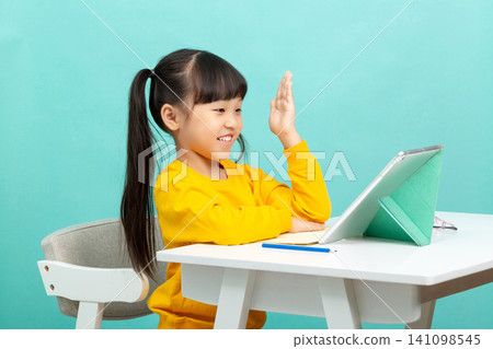 Focused Asian school girl using tablet for online learning isolated on blue background, concentrated emotion, digital education concept Focused Asian school girl using tablet for online learning isolated on blue background, concentrated emotion, digital education concept 141098545