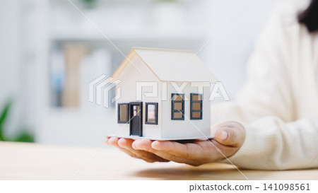 Homeowner holding real estate property model for mortgage insurance, presenting financial protection and investment planning options for buyers purchasing new residential family home Homeowner holding real estate property model for mortgage insurance, presenting financial protection and investment planning options for buyers purchasing new residential family home 141098561