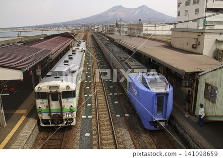 [Station staff member facing in another direction, face hidden] Kiha 281 series and Kiha 40 series trains waiting to depart from JR Mori Station, JR Hokkaido. 141098659