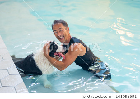 Senior man letting his dog swim in a pool Senior man letting his dog swim in a pool 141098691