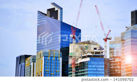 Crane on the construction site in a site surrounded by the high buildings. Office building under construction in the vicinity of high apartment buildings and office building. Crane on the construction site in a site surrounded by the high buildings. Office building under construction in the vicinity of high apartment buildings and office building. 141098702