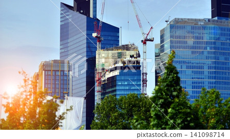 Crane on the construction site in a site surrounded by the high buildings. Office building under construction in the vicinity of high apartment buildings and office building. Crane on the construction site in a site surrounded by the high buildings. Office building under construction in the vicinity of high apartment buildings and office building. 141098714