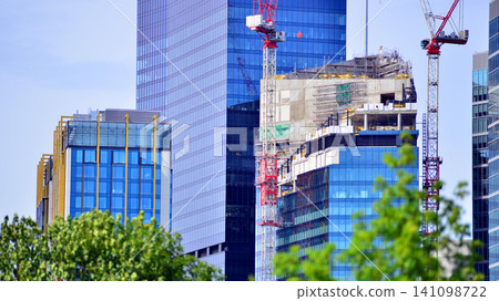 Crane on the construction site in a site surrounded by the high buildings. Office building under construction in the vicinity of high apartment buildings and office building. Crane on the construction site in a site surrounded by the high buildings. Office building under construction in the vicinity of high apartment buildings and office building. 141098722