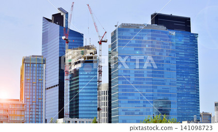 Crane on the construction site in a site surrounded by the high buildings. Office building under construction in the vicinity of high apartment buildings and office building. Crane on the construction site in a site surrounded by the high buildings. Office building under construction in the vicinity of high apartment buildings and office building. 141098723
