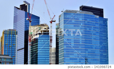 Crane on the construction site in a site surrounded by the high buildings. Office building under construction in the vicinity of high apartment buildings and office building. Crane on the construction site in a site surrounded by the high buildings. Office building under construction in the vicinity of high apartment buildings and office building. 141098724