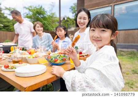 一家三代人在花園裡享受燒烤。 141098779