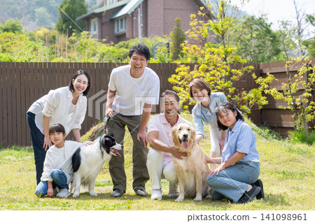 A three-generation family playing with their dog in the yard A three-generation family playing with their dog in the yard 141098961