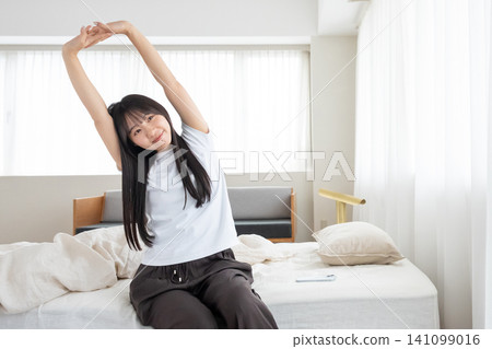 A woman waking up in the morning and stretching A woman waking up in the morning and stretching 141099016