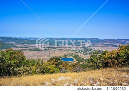A small town at the foot of the mountains. ?illage in a valley between the mountains. Rural landscape. Wooden roofs of houses. Crimea A small town at the foot of the mountains. ?illage in a valley between the mountains. Rural landscape. Wooden roofs of houses. Crimea 141099083