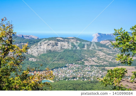 A small town at the foot of the mountains. ?illage in a valley between the mountains. Rural landscape. Wooden roofs of houses. Crimea A small town at the foot of the mountains. ?illage in a valley between the mountains. Rural landscape. Wooden roofs of houses. Crimea 141099084