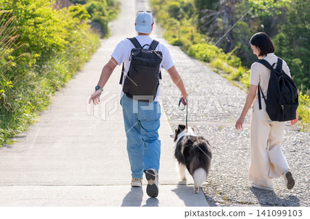 一對夫婦帶著他們的狗享受旅行,這是從背後拍攝的。 一對夫婦帶著他們的狗享受旅行,這是從背後拍攝的。 141099103