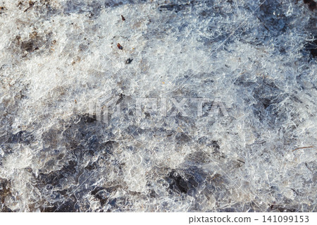 Small dirty broken ice on the ground. The beginning of spring. Broken ice on the ground as a background. Winter Small dirty broken ice on the ground. The beginning of spring. Broken ice on the ground as a background. Winter 141099153