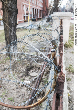 Barbed wire wall. Security barbed wire on a low fence Barbed wire wall. Security barbed wire on a low fence 141099236