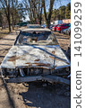 Broken and abandoned old white car. A car with a broken windshield and no wheels on a city street. Garbage inside the old car 141099259