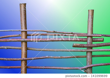 Wooden hedge fence made of branches and cuttings on blue green gradient Wooden hedge fence made of branches and cuttings on blue green gradient 141099699