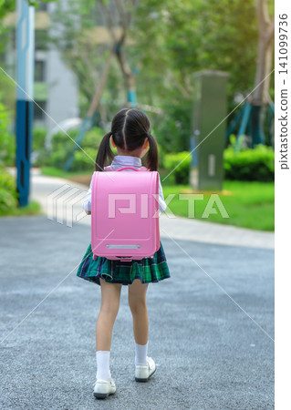 Rear view of a little girl with a pink backpack walking to school, new semester and educational growth. Rear view of a little girl with a pink backpack walking to school, new semester and educational growth. 141099736