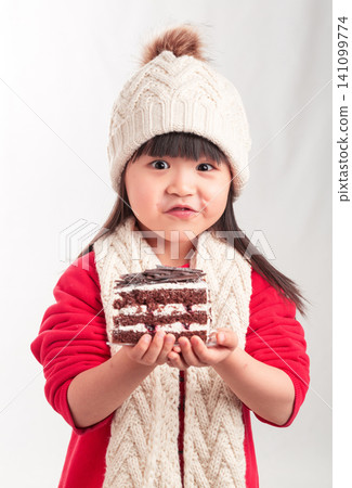 Little girl in winter outfit holding a slice of chocolate cake, dessert and birthday celebration concept. 141099774