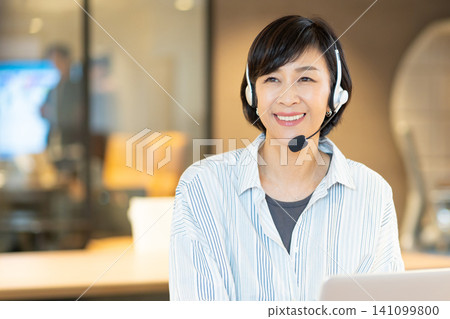 一位微笑的資深女操作員正在使用電腦。 141099800