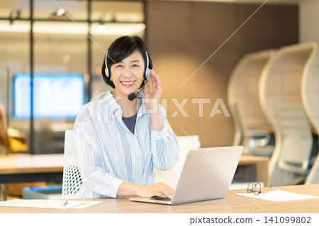 A smiling senior female operator using a computer. A smiling senior female operator using a computer. 141099802