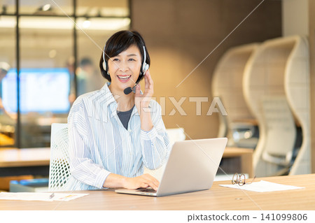 A smiling senior female operator using a computer. A smiling senior female operator using a computer. 141099806