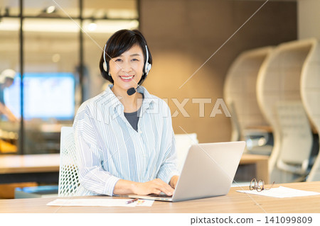 一位微笑的資深女操作員正在使用電腦。 141099809