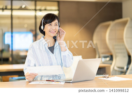 一位微笑的資深女操作員正在使用電腦。 一位微笑的資深女操作員正在使用電腦。 141099812