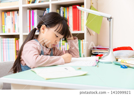 Asian schoolgirl doing homework at desk with books, education and study concentration concept Asian schoolgirl doing homework at desk with books, education and study concentration concept 141099921