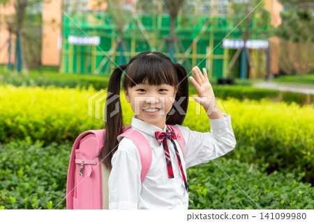 Asian elementary school students carrying their schoolbags happily walk in the city park after school. 141099980