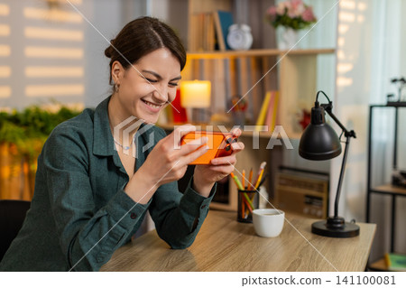 Young woman on home table playing smartphone game winning happy celebrating victory at home indoors Young woman on home table playing smartphone game winning happy celebrating victory at home indoors 141100081