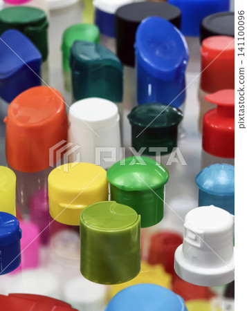 Colorful bottle caps spread out on a flat surface in a variety of shapes and sizes during daylight hours Colorful bottle caps spread out on a flat surface in a variety of shapes and sizes during daylight hours 141100096