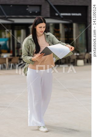 Young woman carrying documents walking in city street nervously rehearsing for job interview meeting Young woman carrying documents walking in city street nervously rehearsing for job interview meeting 141100124