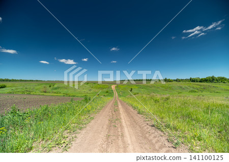Dirt path through green summer fields under a clear blue sky Dirt path through green summer fields under a clear blue sky 141100125