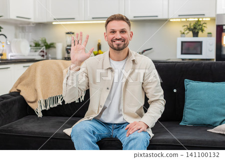 Young man waves hand to camera friendly hello warm greeting smile kind mood casual social video clip Young man waves hand to camera friendly hello warm greeting smile kind mood casual social video clip 141100132