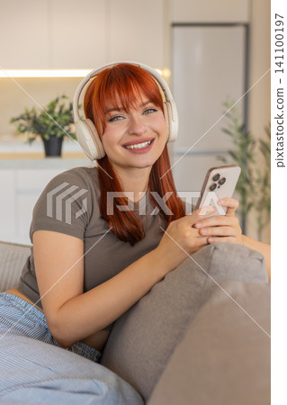 Young woman in wireless headphones listens to music on smartphone relax chill calm mood and breathe Young woman in wireless headphones listens to music on smartphone relax chill calm mood and breathe 141100197