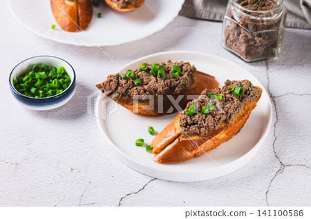 Crispy toasts with liver pate and chives on a plate on the table Crispy toasts with liver pate and chives on a plate on the table 141100586