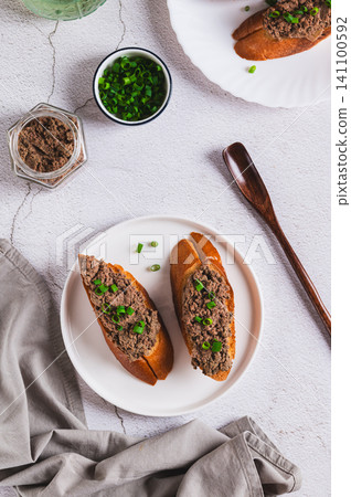 Crispy toasts with liver pate and chives on a plate on the table top and vertical view 141100592