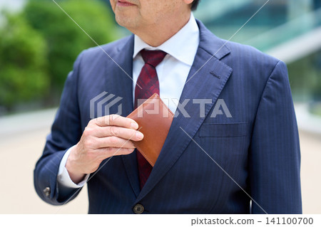 一位亞洲商人從胸前的口袋掏出一個真皮錢包。 141100700