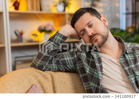 Young man on home sofa falling asleep from exhaustion after tiring work stress and evening burnout Young man on home sofa falling asleep from exhaustion after tiring work stress and evening burnout 141100917