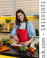 Young woman making fresh vegetable salad in home kitchen for healthy diet weight loss nutrition plan 141101071