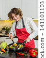 Young woman cooking healthy vegetables in pan for diet meal while enjoying fresh home food routine 141101103