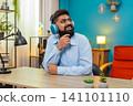 Indian man listens music on headphones moves to rhythm enjoying beat relaxing indoors energetic vibe 141101110