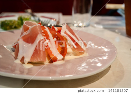 Appetizer dish featuring prosciutto and tomatoes Appetizer dish featuring prosciutto and tomatoes 141101207