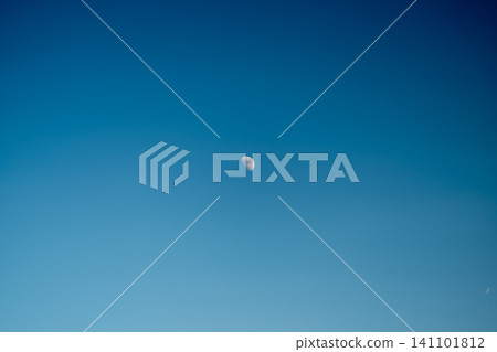 Small crescent moon high in clear blue sky with subtle color gradient Small crescent moon high in clear blue sky with subtle color gradient 141101812