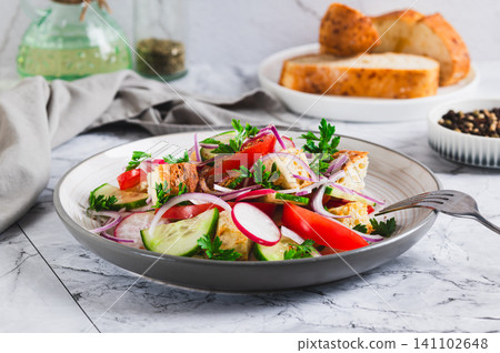 Fresh salad of tomatoes, cucumbers, radishes, onions and croutons on a plate on the table Fresh salad of tomatoes, cucumbers, radishes, onions and croutons on a plate on the table 141102648