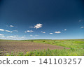 Wide rural field under blue sky with scattered clouds Wide rural field under blue sky with scattered clouds 141103257